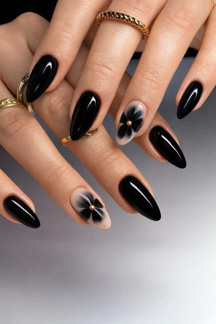 Glossy black almond nails with floral accent